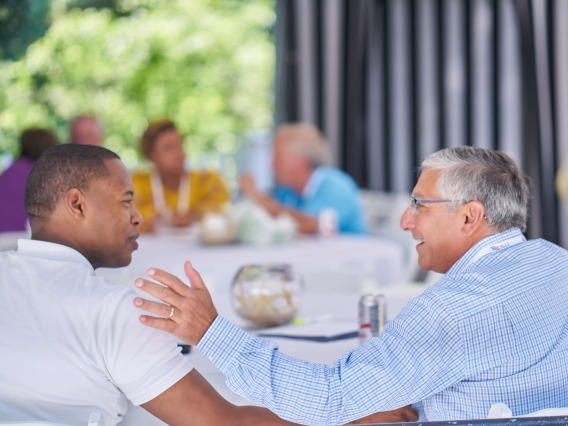 two business men talking at an outdoor group table